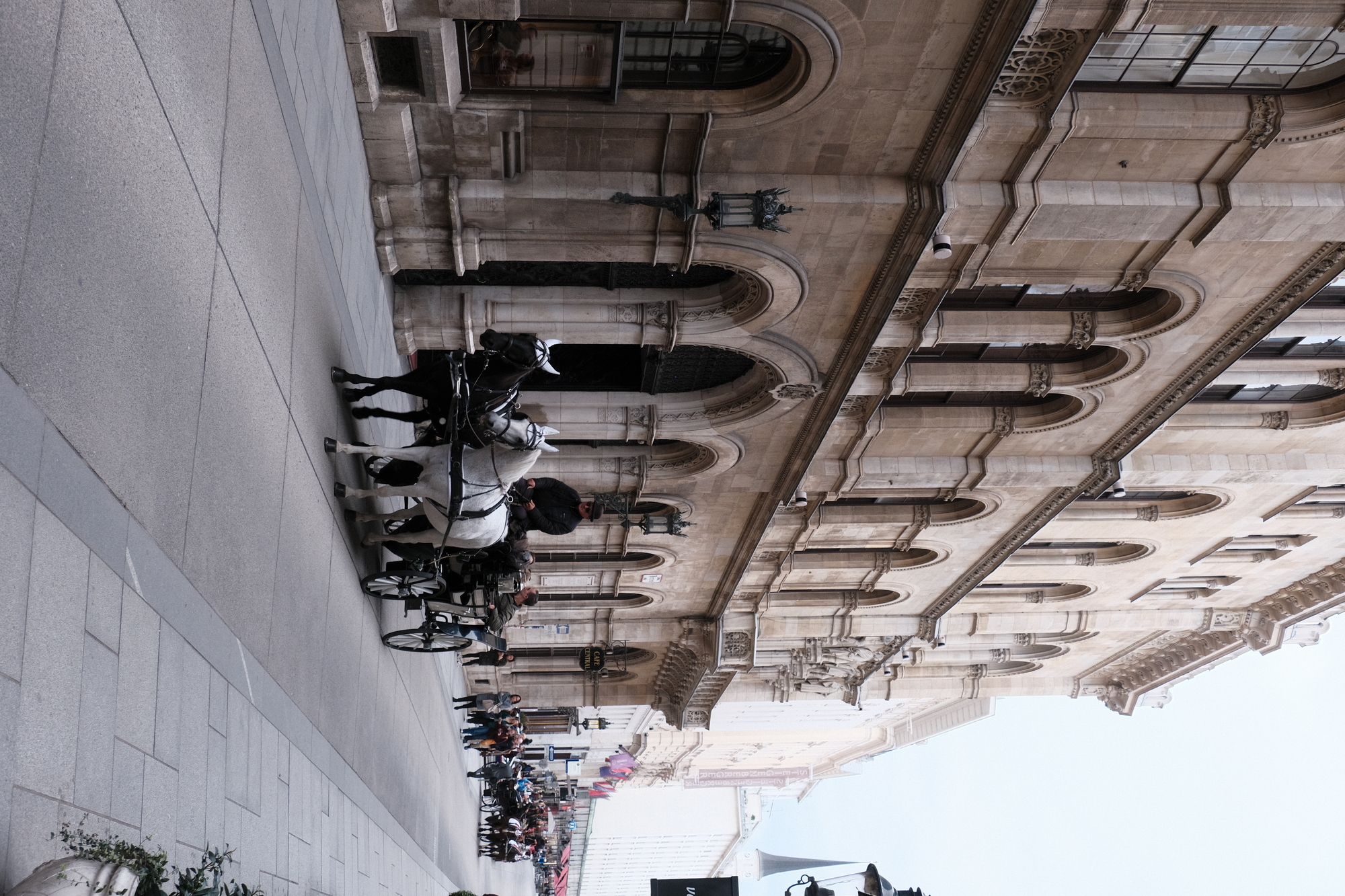 a horse drawn carriage with passengers amidst stone buildings